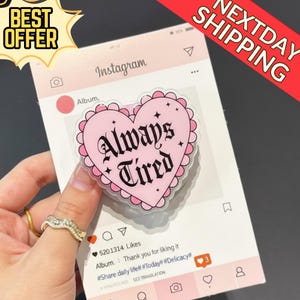 May include: A pink heart-shaped sticker with the words "Always Tired" in black gothic font. The sticker is on a mock Instagram post with a pink background. The image also includes the text "Best Offer" and "Next Day Shipping".