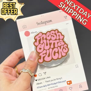 May include: A clear phone grip with the phrase "Fresh Outta Fucks" in pink and brown lettering. The grip is on a pink and white Instagram-themed background with the words "Best Offer" and "Next Day Shipping".