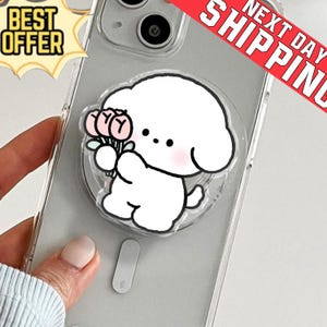 May include: Clear phone case with a cartoon dog holding flowers. The dog has a white body, black eyes, and pink cheeks. The case has a pop-up grip. The words "BEST OFFER" are in a yellow banner.