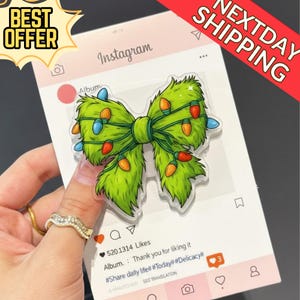 Może przedstawiać: Przezroczysta akrylowa kokarda świąteczna z zieloną fakturą przypominającą futro, ozdobiona kolorowymi światełkami. Kokarda jest prezentowana na tle karty w stylu Instagram z tekstem "BEST OFFER" i "NEXTDAY SHIPPING".