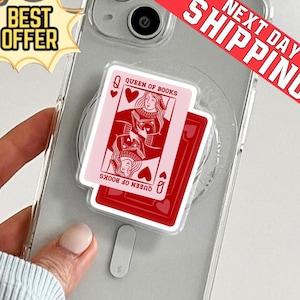 May include: A phone grip featuring a playing card design. The top card is a pink Queen of Books with a heart suit, and the bottom card is red. The phone is in a clear case, with a "Best Offer" and "Next Day Shipping" banner.