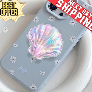 May include: A light blue phone case with a daisy pattern and a holographic seashell phone grip. The case has the text "Bonne Case" and is on a white plate. The image also has the text "Best Offer" and "Next Day Shipping".