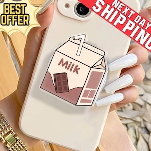 May include: A phone case featuring a milk carton design. The carton is light brown with a chocolate bar illustration and the word "Milk". The phone case is held by a person.