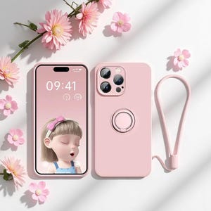 Puede incluir: Una funda de teléfono rosa claro con una correa de muñeca a juego y un teléfono que muestra una imagen de dibujos animados. La funda del teléfono tiene un soporte de anillo en la parte posterior. Flores rosas están esparcidas alrededor del teléfono y la funda.