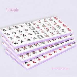 May include: A set of white mahjong tiles with purple backs, featuring black and red engraved characters, floral designs, and seasonal labels. The tiles are arranged in stacks, with text on the tiles indicating directions and seasons. Size: 30x22.5x12.5mm.