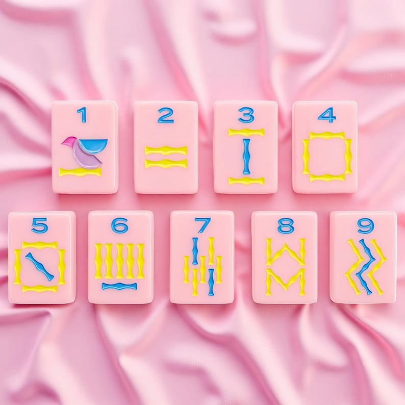 May include: A set of nine rectangular pink tiles arranged in two rows, each featuring a blue numeral from one to nine at the top and various yellow and blue geometric or abstract symbols below, all presented with a smooth, matte finish.
