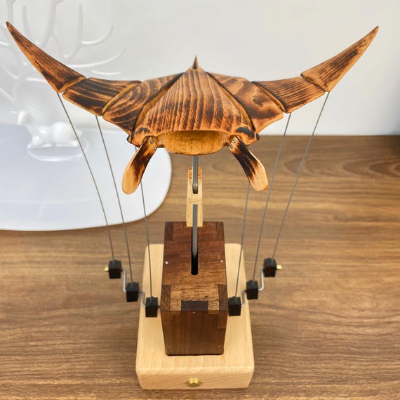 A wooden manta ray that actually flies in mechanical motion — sculptural sea-life kinetic art that looks like it belongs in a design museum.