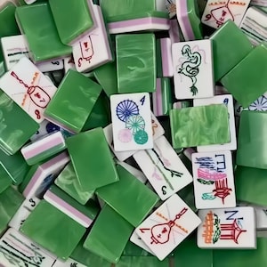 May include: A collection of green and white Mahjong tiles. The tiles feature various symbols, numbers, and illustrations in red, black, and green. Some tiles are solid green, while others have pink and white accents. The game pieces are scattered.