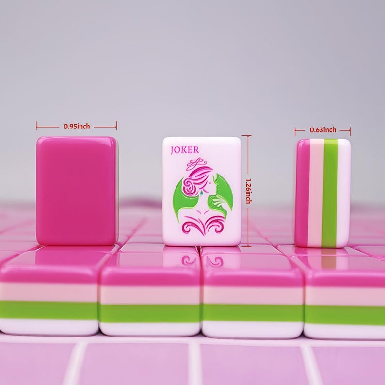 May include: A close-up of pink and white Mahjong tiles. One tile is solid pink, measuring 0.95 inches wide. Another tile features a woman graphic and the word "JOKER". A third tile has pink, green, and white stripes, measuring 0.63 inches wide. The tiles are 1.26 inches tall.