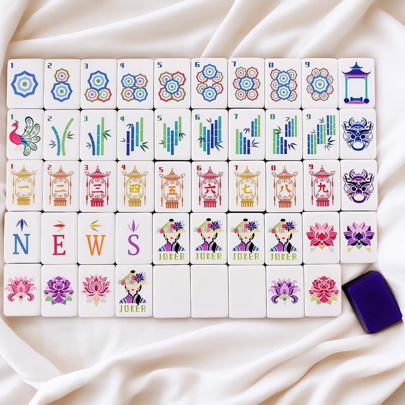 May include: A full Mahjong set with white tiles displaying colourful symbols, numbers, and characters. The set includes tiles with floral designs, bamboo, and the word "NEWS". A purple tile holder is also included.