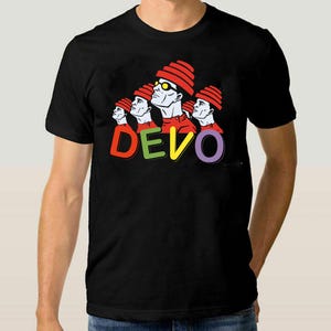 May include: Black t-shirt with a colourful graphic of a band wearing red hats and the word "DEVO" in rainbow colours. The band members have white faces and red shirts. The design is in a vibrant pop art style.