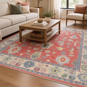 May include: A rectangular area rug featuring a vibrant coral red field with a central medallion pattern in shades of light blue, cream, and sage green. The rug has a wide cream-colored border with blue and green floral motifs and geometric shapes.