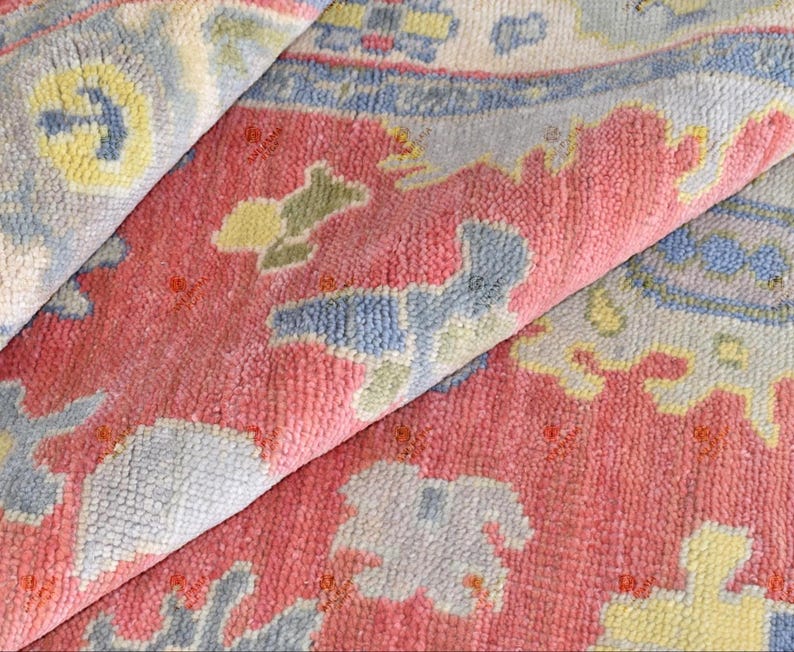 Vintage Oushak rug in pink-red wool with pale blue border and ivory floral motifs; hand-knotted, handmade wool rug.