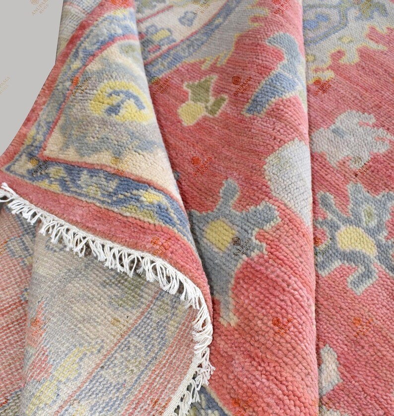 Vintage Oushak rug in pink-red wool with pale blue border and ivory floral motifs; hand-knotted, handmade wool rug.