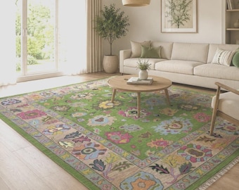 May include: A large rectangular area rug featuring a vibrant green background with a multi-coloured floral pattern in shades of pink, blue, yellow, and brown. The rug has a wide decorative border and short fringe along the edges.