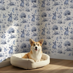May include: A tan and white corgi dog sits in a cream-colored dog bed in front of a wallpaper with a blue and white toile pattern. The wallpaper features corgis, trees, and floral elements.