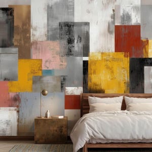 May include: Abstract art mural with a patchwork design in shades of gray, white, yellow, red, and black. A wooden bed frame with white bedding and a nightstand with a lamp and decor are in the foreground.