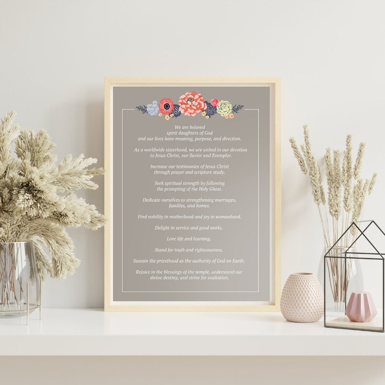 May include: A framed print with a gray background and a floral border. The print features a list of inspirational quotes for women, including "We are beloved spirit daughters of God" and "Increase our testimonies of Jesus Christ through prayer and scripture study."