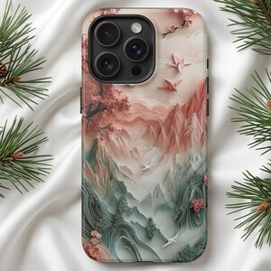 Könnte beinhalten: Handyhülle mit einem Landschaftsdesign, das Berge, Bäume und fliegende Vögel in Rosa, Grün und Weiß zeigt. Die Hülle hat eine glänzende Oberfläche und einen Kameraausschnitt.
