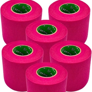 May include: A collection of six rolls of bright pink athletic tape. Each roll has a green and white label in the center. The tape is tightly wound and appears to be new.