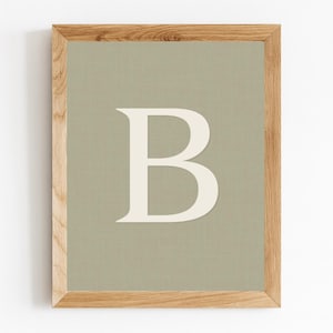 May include: A framed print featuring a large, off-white letter "B" against a muted green background. The print is encased in a natural wood frame, creating a simple yet elegant aesthetic. Ideal for home decor.
