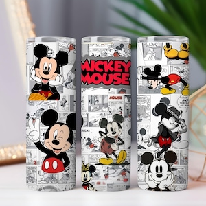 May include: Three white insulated tumblers featuring Mickey Mouse. Each tumbler showcases different poses of Mickey against a black and white comic strip background. The center tumbler has "Mickey Mouse" in red text.