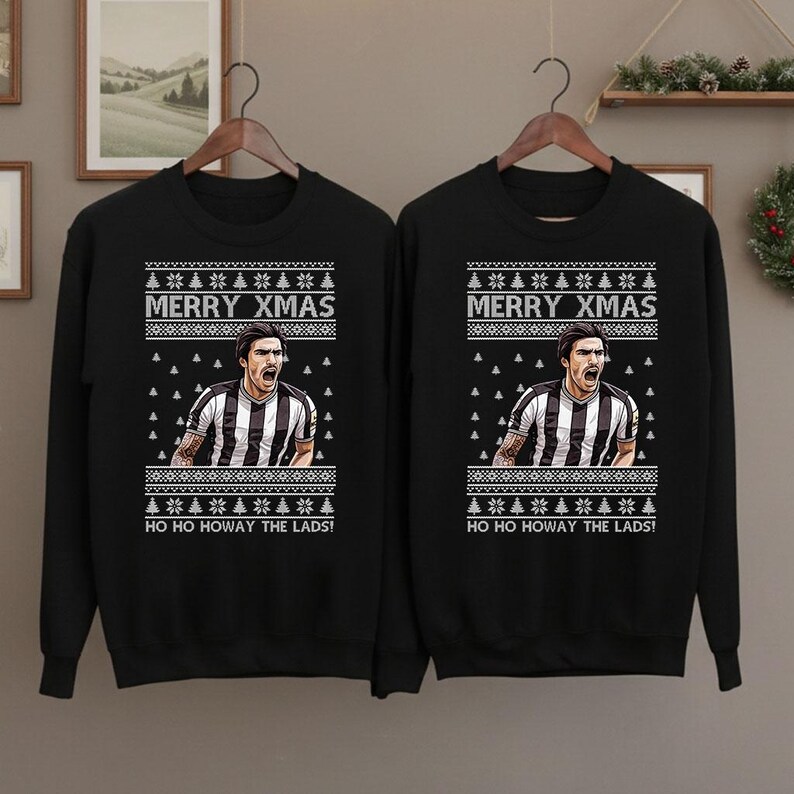 May include: Black sweatshirt with a festive design. The design includes the text "MERRY XMAS" above an image of a soccer player in a black and white striped jersey. Below the image is the text "HO HO HOWAY THE LADS!"