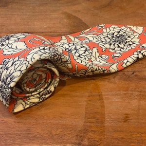 Front  and right side and rolled up view of vintage silk Chrysanthemum Floral Print in white  over orange Vintage 5 fold scarf with cream backing or lining of the tie