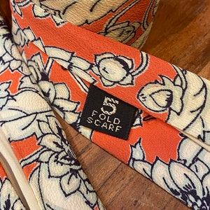 Back view and closeup of tag showing 5 fold scarf of vintage silk Chrysanthemum Floral Print in white  over orange  with cream backing or lining