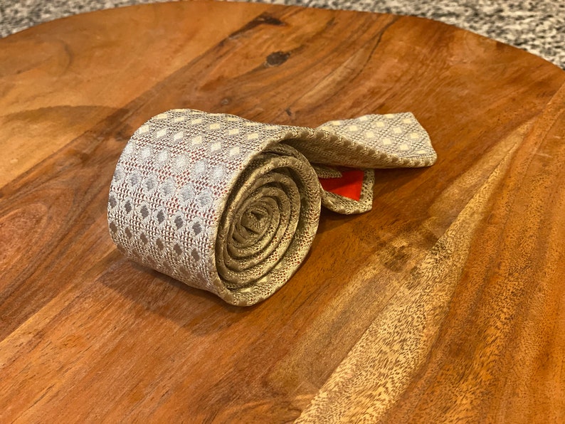 Rolled up Vintage John Northman New York Tie Silver / Gray mesh silk knit tie over coral color silk backing Hand tailored loomed in Italy