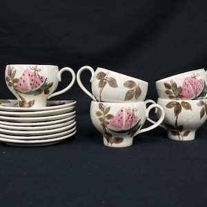 May include: Set of six vintage teacups and saucers with a watermelon design. The cups and saucers are white with brown and pink accents. The cups have a rounded shape and a handle on the side. The saucers are round and have a slight lip.