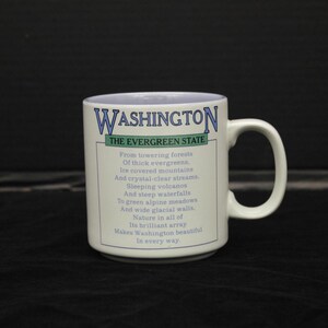 May include: White ceramic mug with a blue and green design. The mug features a poem about the state of Washington, titled "The Evergreen State".