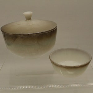 May include: A white ceramic sugar bowl with a lid and a matching smaller bowl. The bowl has a brown glaze that fades to white.