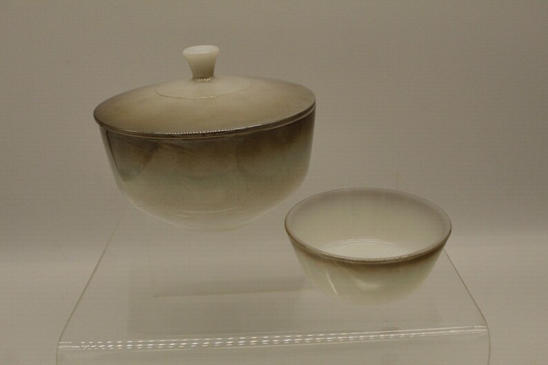 May include: A white ceramic sugar bowl with a lid and a matching smaller bowl. The bowl has a brown glaze that fades to white.
