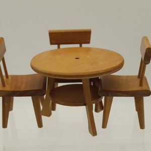 May include: A wooden dollhouse furniture set with a round table and three chairs. The table and chairs are all made of light brown wood.
