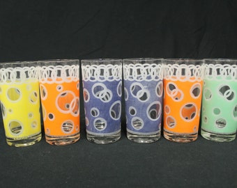 May include: Set of six vintage drinking glasses with a white circle pattern on a colored background. The glasses are yellow, orange, blue, light blue, orange, and green.