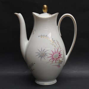 May include: White porcelain coffee pot with a gold trim and floral design. The pot has a rounded body and a curved handle.