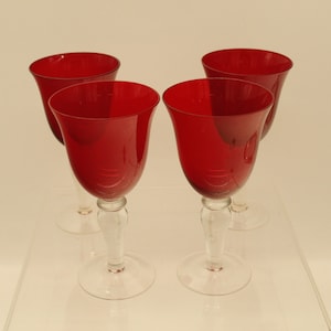 May include: Set of four red wine glasses with clear stems and bases. The glasses are made of glass and have a classic design.