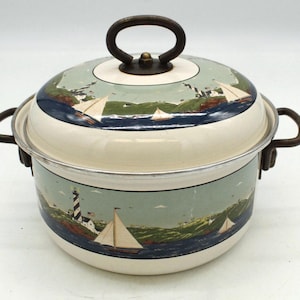 May include: Cream-colored enamelware pot with a lid, featuring a nautical scene with sailboats, a lighthouse, and coastal landscapes. The pot has dark brown handles and a matching lid handle. The design includes shades of blue, green, and white.