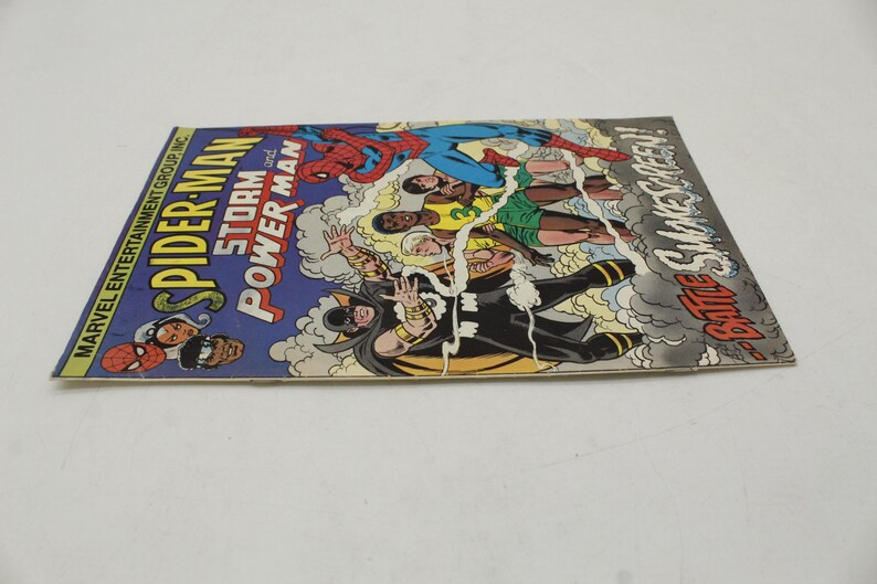 May include: A vintage comic book titled "Spider-Man Storm and Power Man" with colorful illustrations of superheroes in action. The cover features Spider-Man, and other characters in a dynamic battle scene. The comic book is in good condition.