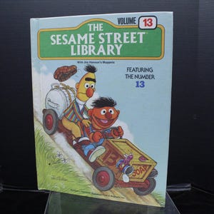 May include: The Sesame Street Library, Volume 13, features the number 13.  Big Bird and Elmo are on a red toy truck with a white box that says "SOAP".