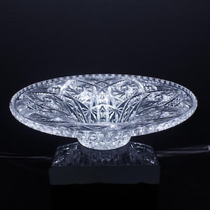 May include: A clear glass bowl with a pedestal base. The bowl has a cut glass design and is perfect for serving fruit or snacks.