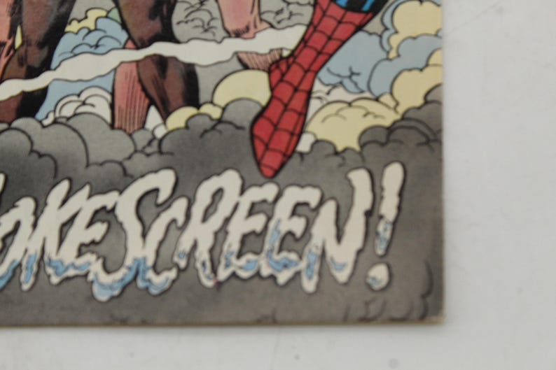 May include: Comic book panel featuring Spider-Man's red and blue costume, with the word "OKESCREEN!" in a stylized font. The artwork includes gray and white clouds, and other figures are partially visible.