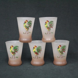 May include: Set of five frosted glass drinking glasses with a rooster design. Each glass features a yellow rooster with red and green accents on a brown background.