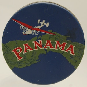 May include: A blue and green round tin with a red airplane flying over a map of Panama. The text "PANAMA" is in red letters.