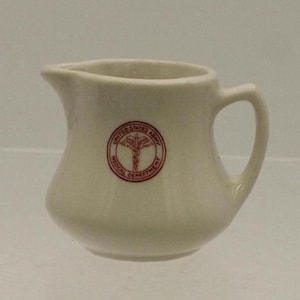May include: White ceramic creamer with a red United States Army Medical Department logo.