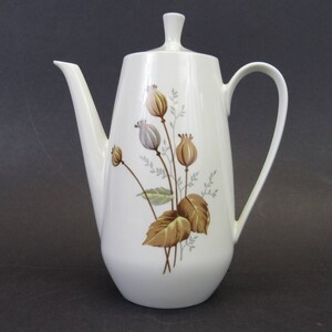 May include: A white ceramic coffee pot with a tall, slender design. It features a floral pattern in shades of brown, tan, and gray. The pot has a long spout, a curved handle, and a lid with a small knob. A vintage-style coffee server.