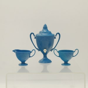 May include: A blue vintage tea set, including a lidded urn-shaped teapot with handles, a creamer, and a sugar bowl. The set has a floral pattern and is made of ceramic.