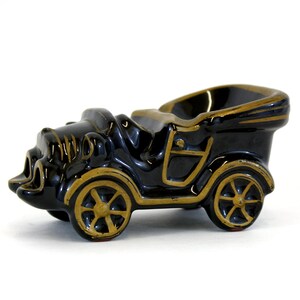 Redware ashtray that looks like an old car with the convertible top down. Black glaze and gold detailing. Good condition.