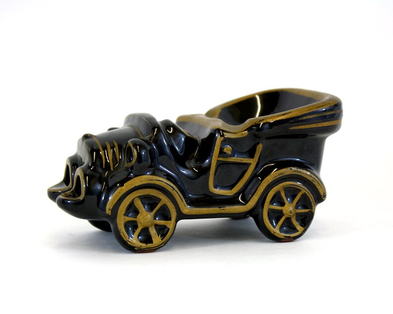 Redware ashtray that looks like an old car with the convertible top down. Black glaze and gold detailing. Good condition.